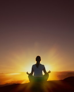 Woman meditating at sunset