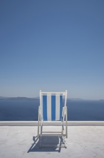 Striped deck chair on balcony by sea in Santorini, Greece