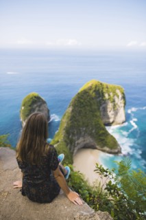 Woman sitting above Kelingking Beach in Nusa Penida, Indonesia