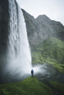 Man standing by Seljalandsfoss waterfall in Iceland