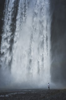 Man standing by Skogafoss waterfall in Iceland