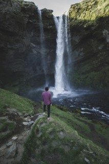 Man standing by Kvernufoss waterfall in Iceland