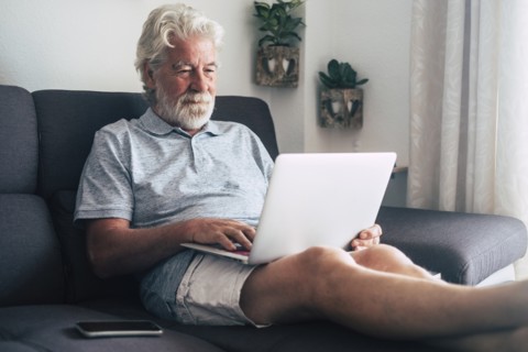 Senior man using laptop on sofa