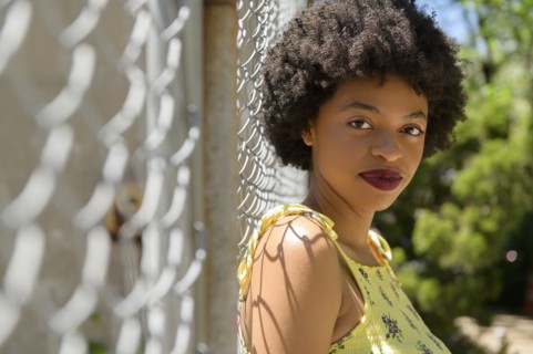 Portrait of young woman by wire fence