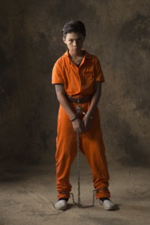 Boy in prisoner jumpsuit and handcuffs