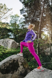 Woman wearing sportswear on rocks in forest