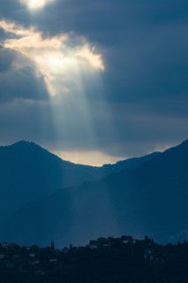 Sunbeams through clouds over mountains in Lombardy, Italy