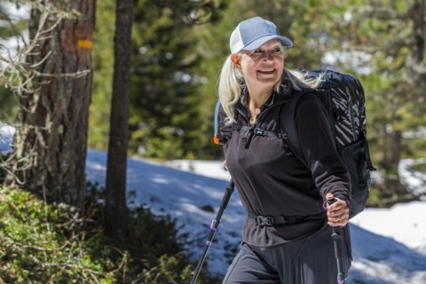 Mature woman hiking by trees on Munkel Trail in Val di Funes, Italy