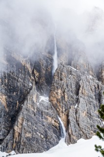Snow falling down cliff in Dolomites, Italy