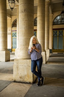 Woman using smart phone by columns of Palais-Royal in Paris, France