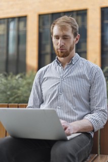 Bearded man using laptop outdoors