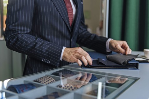 Shop assistant wearing pinstripe suit holding swatches