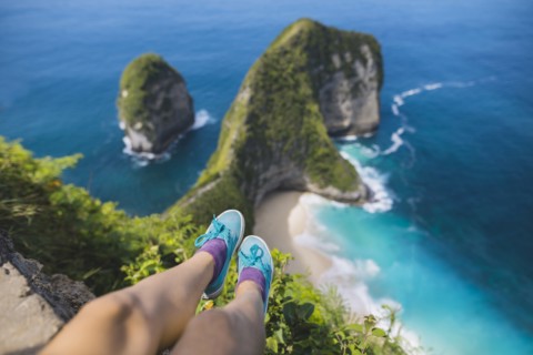 Legs of woman sitting above Kelingking Beach in Nusa Penida, Indonesia