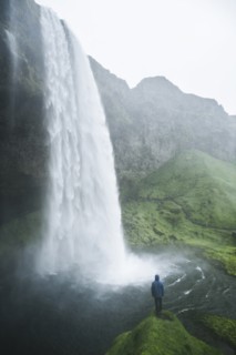 Man standing by Seljalandsfoss waterfall in Iceland