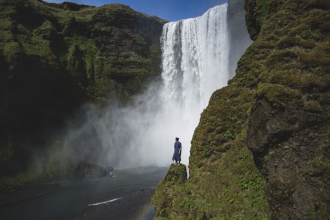 Man standing by Skogafoss waterfall in Iceland