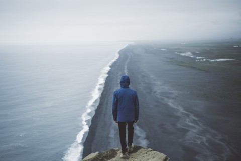 Man wearing blue coat above beach in Vik, Iceland