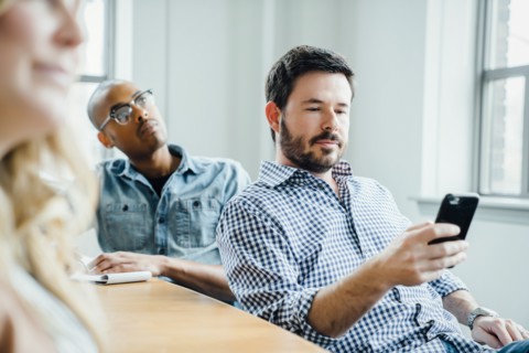 Man holding smart phone during meeting