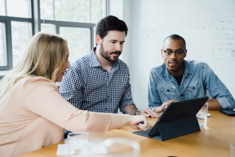 Coworkers using digital tablet in board room