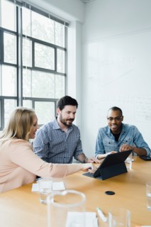 Coworkers using digital tablet in board room