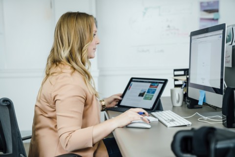 Woman using digital tablet and computer in office
