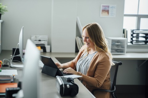 Smiling woman using digital tablet in office