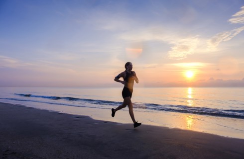 Woman jogging on beach at sunset