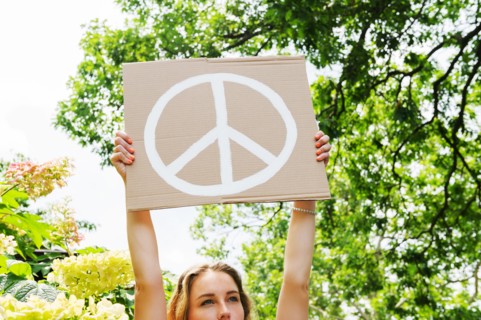 Young woman holding aloft peace symbol