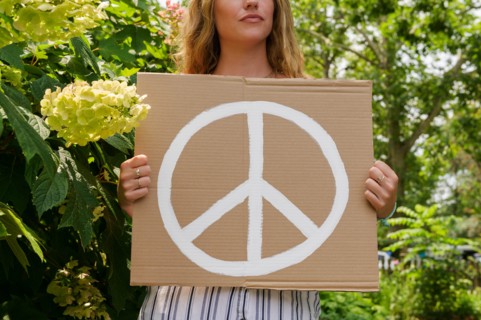 Woman holding peace symbol by trees