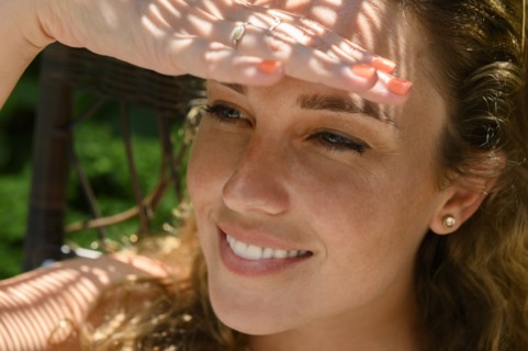 Smiling young woman shielding her eyes