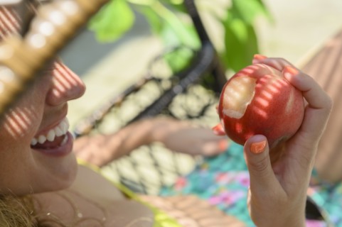 Smiling young woman holding bitten apple