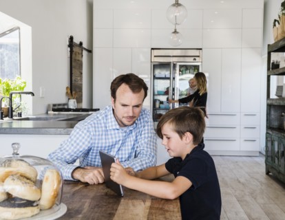 Father and son using digital tablet at dining table