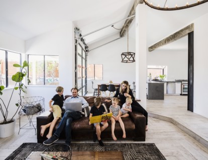Family with book and laptop on sofa