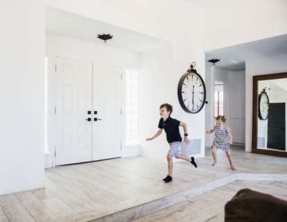Girl chasing her brother in entrance hall