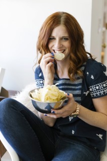 Smiling woman eating crisps from bowl