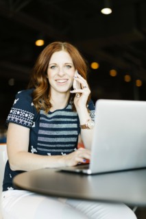 Smiling mid adult woman using smart phone and laptop