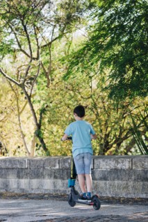Boy using electric scooter on sidewalk
