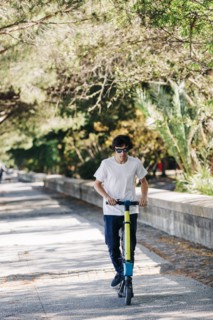 Young man using electric scooter on pavement