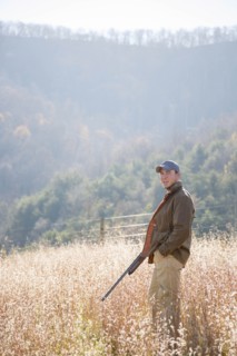 Young man holding rifle in field