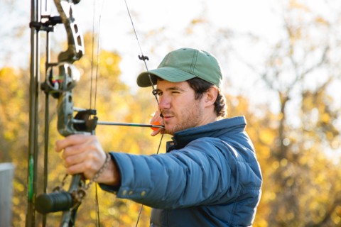 Young man aiming bow and arrow