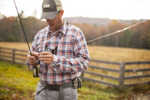 Man holding fishing rod by field