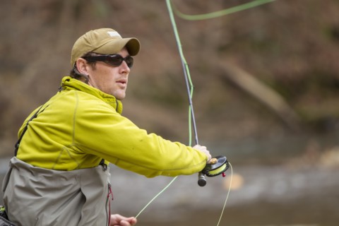 Young man fly-fishing in river