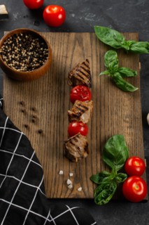 Grilled meat and tomato skewer on cutting board