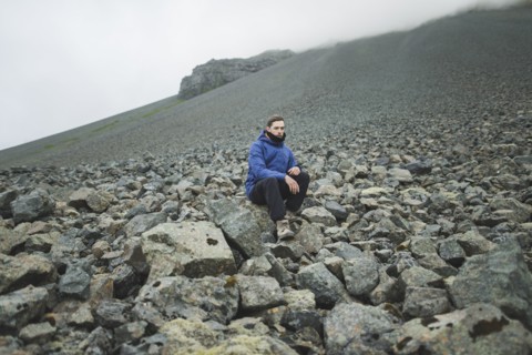 Young man sitting on rock hill in Kirkjubµjarklaustur