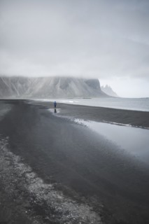 Man walking on black sand beach in Kirkjubµjarklaustur