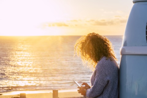 Woman using smart phone by beach at sunset in Fuerteventura