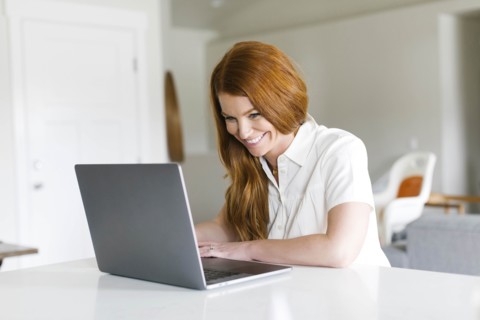 Smiling woman using laptop at home