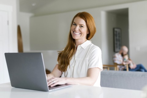 Smiling woman using laptop at home