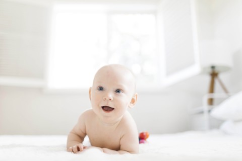 Shirtless baby boy lying on bed
