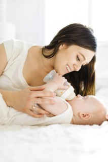 Mother watching her baby boy drink milk from bottle