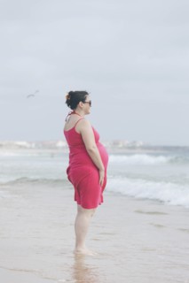 Pregnant woman wearing pink dress on beach
